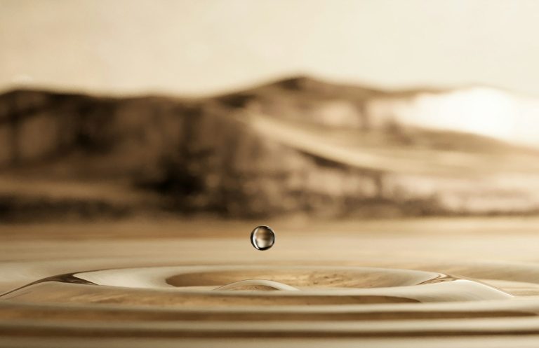 Motivation und Lernen Wassertropfen fällt auf eine ruhige Oberfläche und erzeugt konzentrische Wellen.