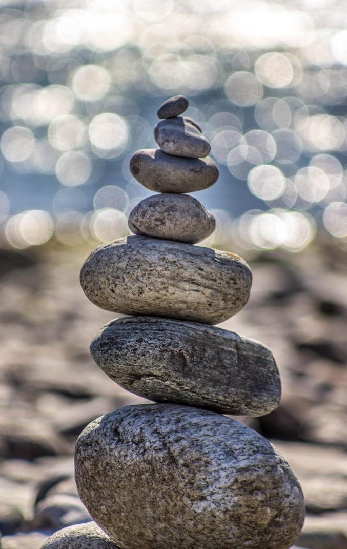 GOLDGRUND ADHS Balance Geschichteter Steinhaufen mit unscharfem, glitzerndem Hintergrund.