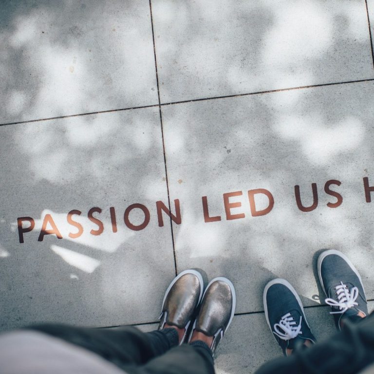 Sicht auf den Boden mit dem Schriftzug „Passion led us here“ und zwei Paar Schuhen.