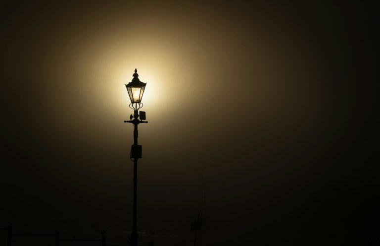 Führung in einer unsicheren Welt Laterne vor einem nebligen, dunklen Hintergrund mit diffusem Lichtschein.